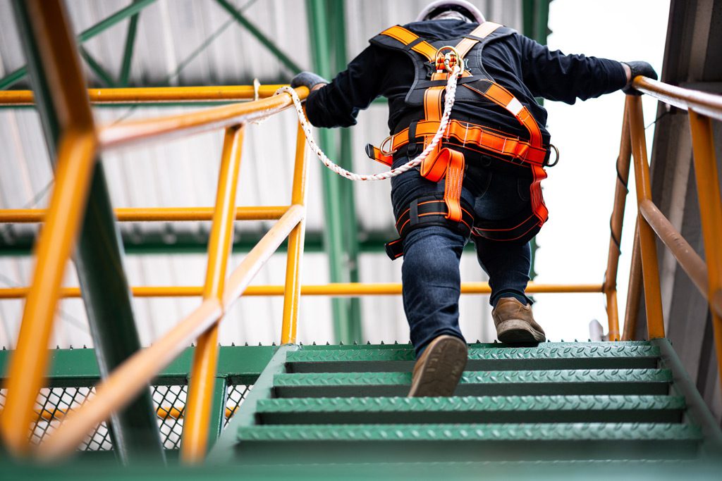 Construction-worker-wearing-safety-harness-while-climbing-stairs