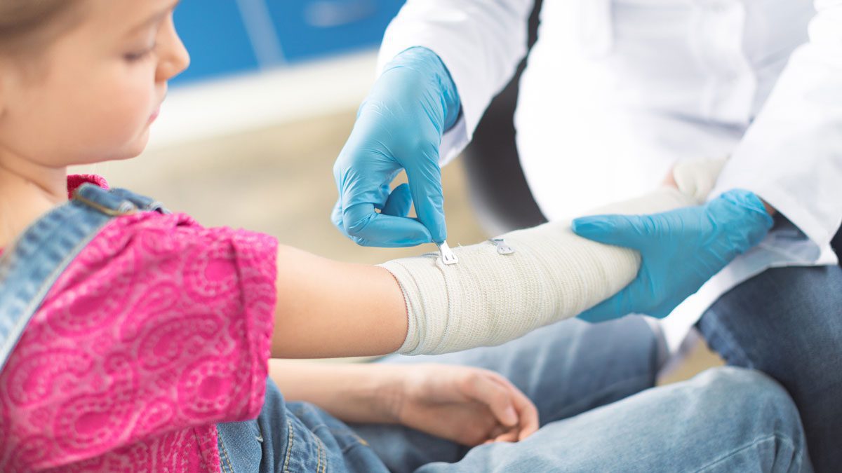 Doctor-bandaging-young-girl’s-hand
