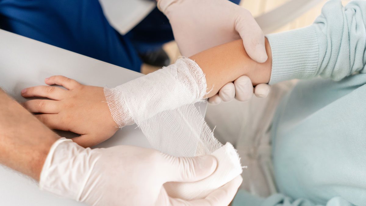 Doctor-wrapping-elastic-bandage-around-boy’s-arm