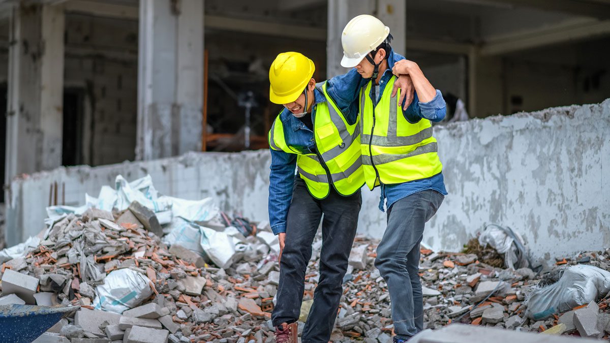 Injured construction worker being helped across debris site