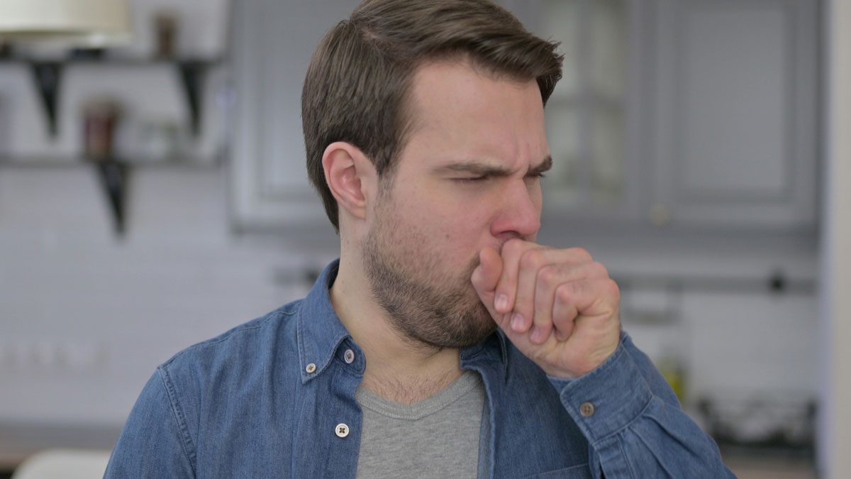 Man coughing into hand showing signs of illness
