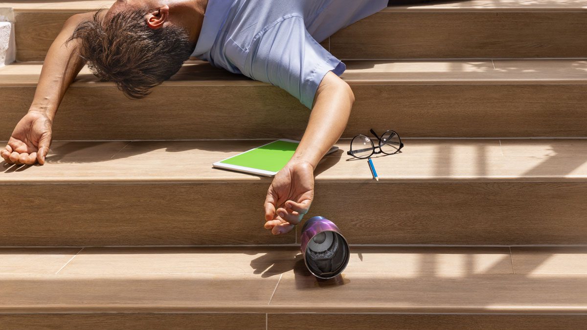 Man lying motionless on stairs with belongings scattered