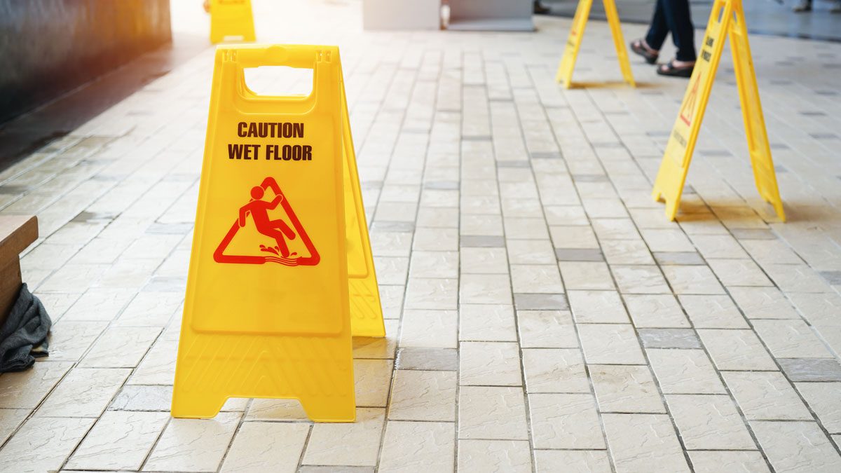 Multiple wet floor signs along tiled walkway