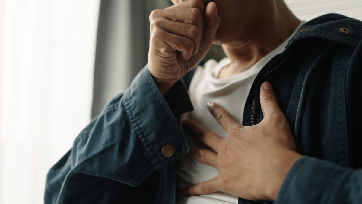 Person clutching chest while coughing in discomfort