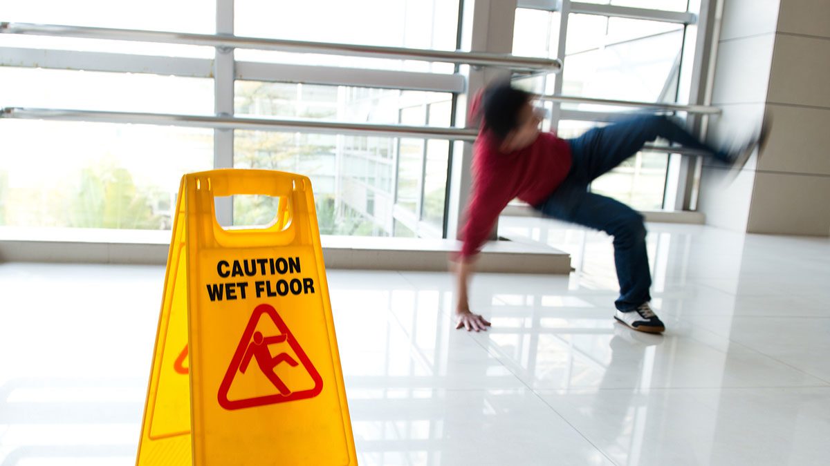 Person slipping near wet floor caution sign