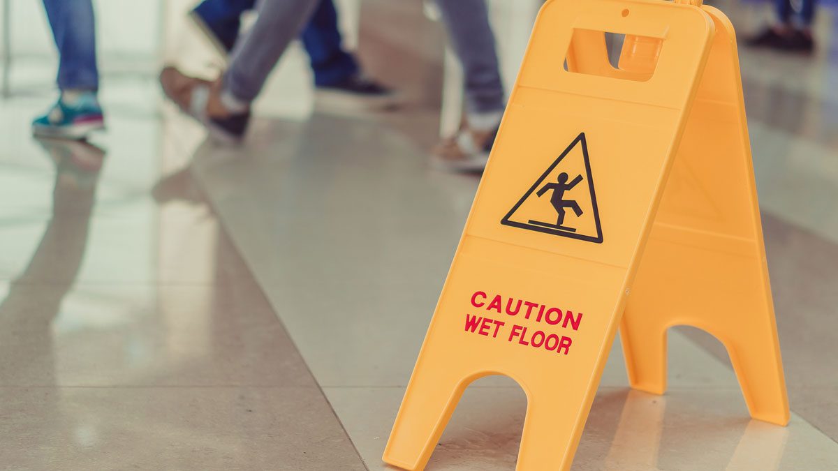 Wet floor caution sign with people walking nearby