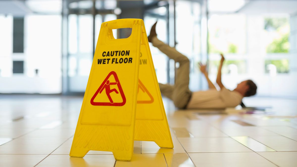 Wet floor sign with person falling in background