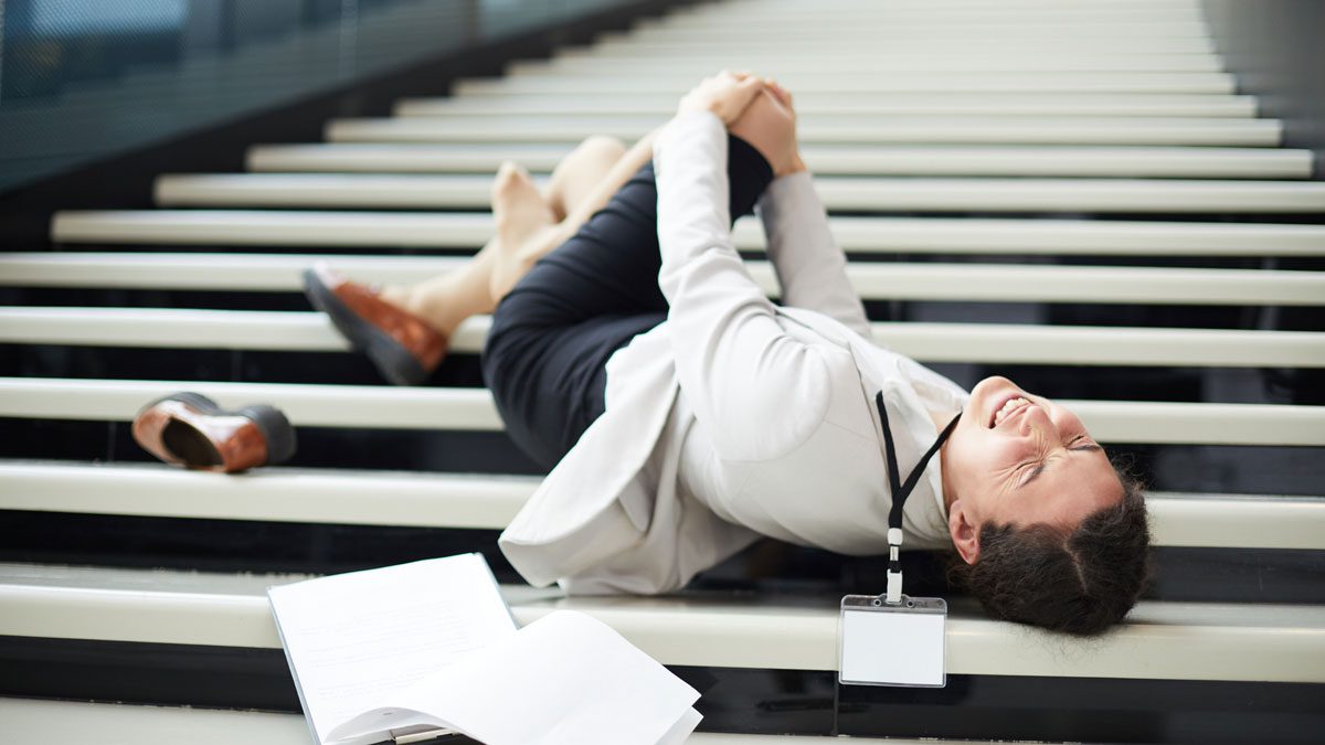 Woman-lying-on-stairs-clutching-knee-in-pain