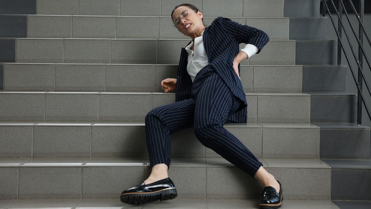 Woman-lying-on-stairs-holding-back-in-pain