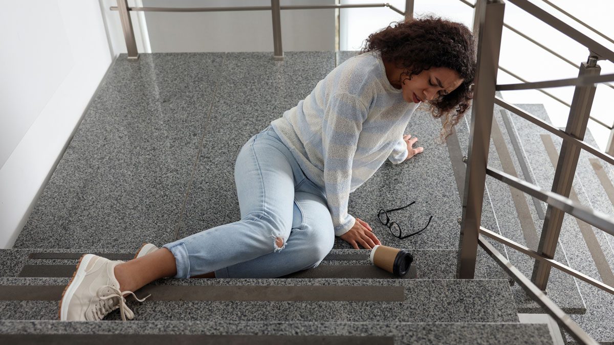 Woman on stairs holding leg after slipping