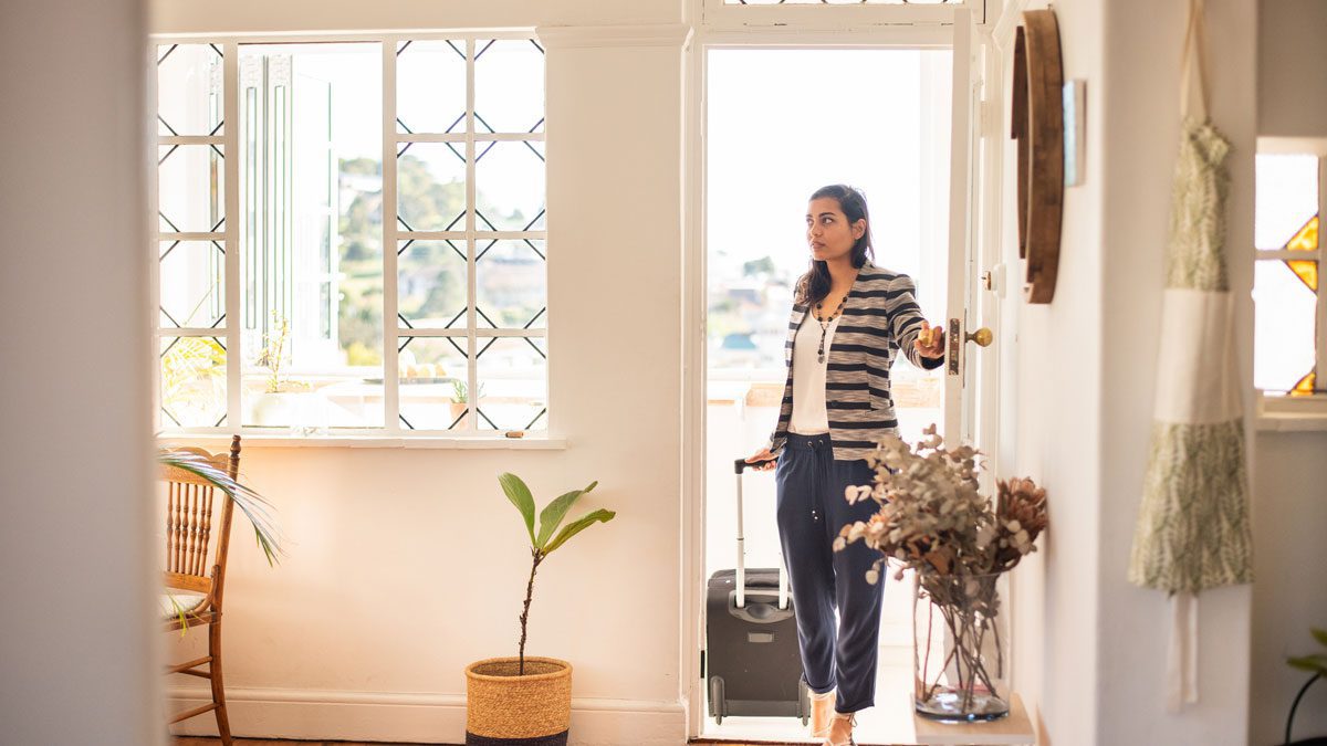 Woman-pulling-suitcase-while-entering-apartment-door