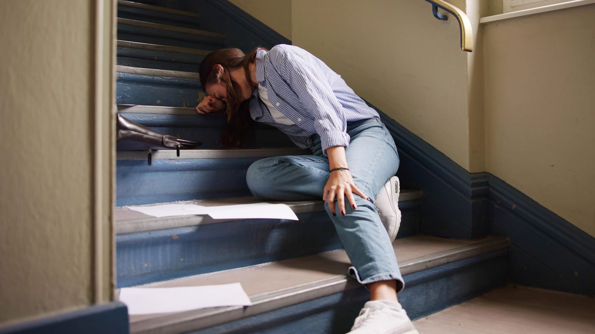 Woman seated on stairs after fall holding head
