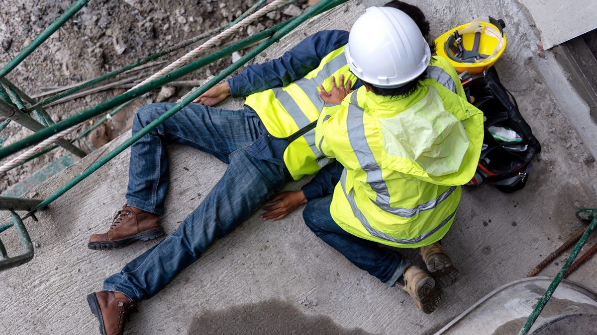 Worker collapsed on ground receiving emergency assistance