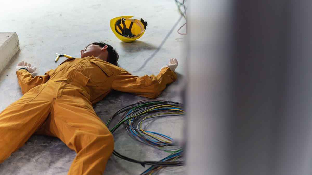 Worker lying on floor near exposed electrical wires