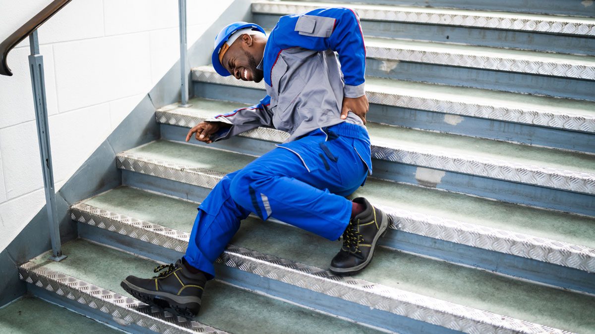 Worker on stairs holding back after fall