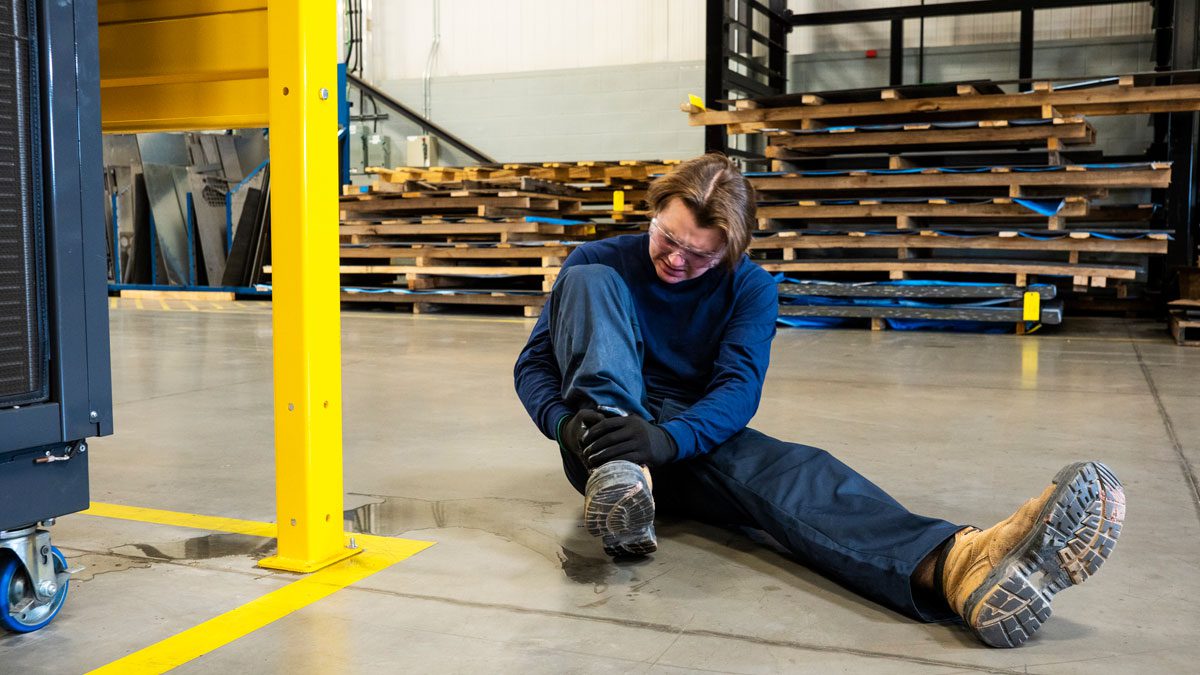 Worker sitting on floor holding injured ankle