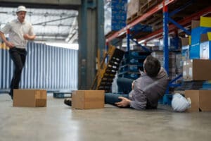 worker-on-the-floor-of-a-warehouse-after-a-fall-while-a-coworker-approaches